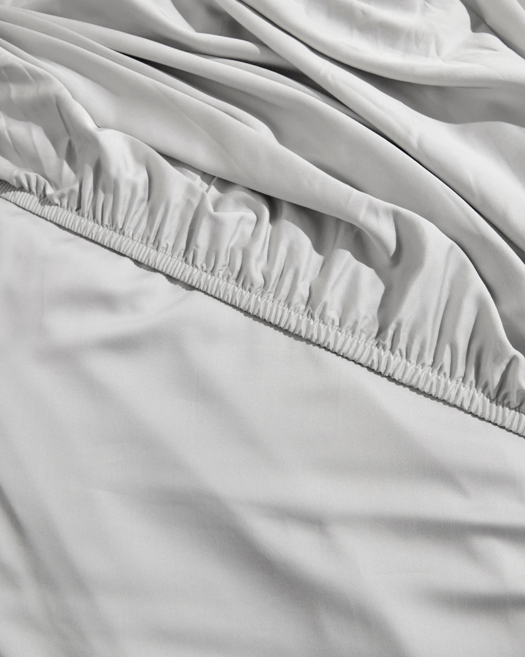 Close-up of light gray fitted sheet with elastic waistband