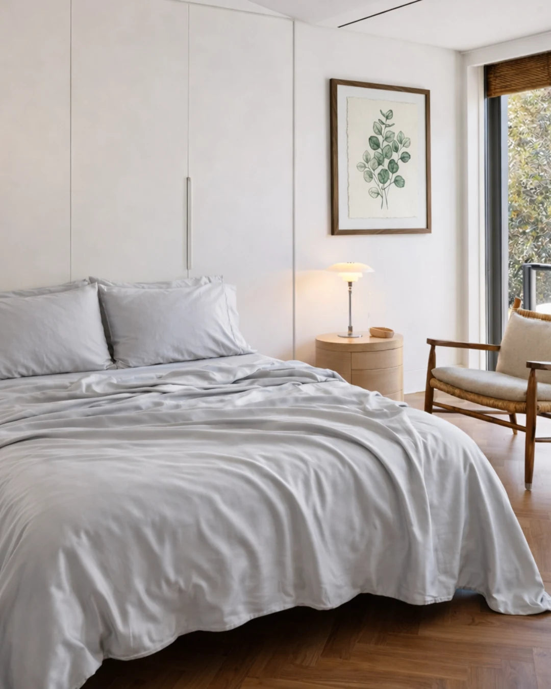 Neatly made bed in a bedroom with a lamp and chair in the background.