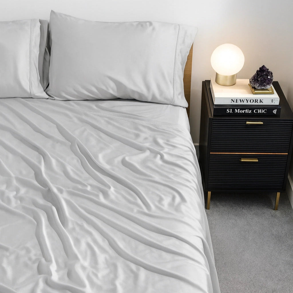 Eucora Light grey bedding set on a bed with a nightstand featuring a lamp and books.
